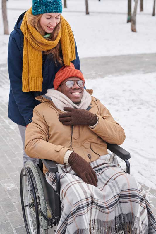 Jeune femme aidant un homme en fauteuil roulant